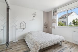 ein weißes Schlafzimmer mit einem Bett und einem Fenster in der Unterkunft Le Lussac - Saint Cyr in Saint-Cyr-lʼÉcole