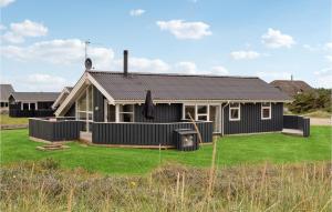 una casa negra con un césped verde delante de ella en Beautiful Home In Harbore With Sauna, en Harboør