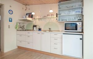 a kitchen with white cabinets and a microwave at One-Bedroom Holiday Home In Vejers Strand in Vejers Strand +6 photos