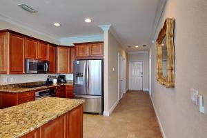 Una cocina con gabinetes de madera y un refrigerador de acero inoxidable. en Beach Club #1804C, en Pensacola Beach
