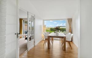 a dining room with a table and white chairs at Lovely Home In Jgerspris With House Sea View in Jægerspris