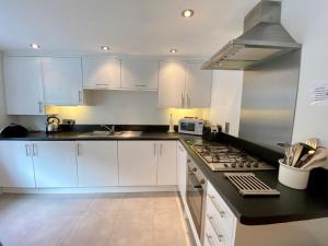 a kitchen with white cabinets and a stove top oven at Florabil in Sidbury