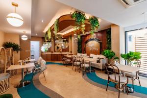 a restaurant with tables and chairs and plants at The Proud Rawai Resort in Rawai Beach