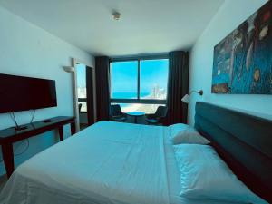 a hotel room with a bed and a large window at Sea Breeze Studios in Netanya