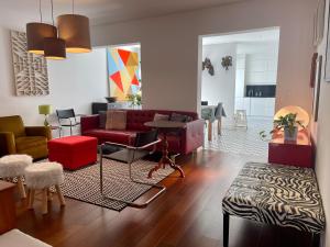 ein Wohnzimmer mit einem roten Sofa und Stühlen in der Unterkunft Casa Amiluz in Ponta Delgada