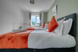 a large bed with orange and white pillows at Luxurious Birmingham Home Private Parking WiFi - near to NEC and QEH in Longbridge