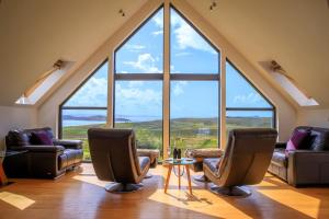 a living room with three chairs and a large window at Locholly Lodge in Achiltibuie