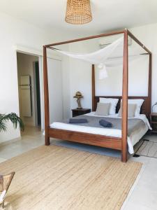 a bedroom with a canopy bed with a wooden frame at ferme st pierre suite, piscine, clim, repas, cheminée in Chabeuil