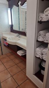 La salle de bains est pourvue d'un lavabo, d'un miroir et de serviettes. dans l'établissement studio village vacance sainte luce C5, à Sainte-Luce