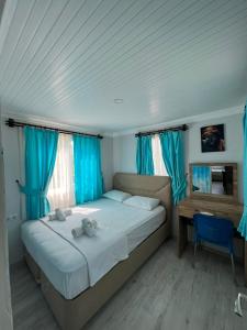 a bedroom with a bed with blue curtains and a desk at ZEYOS LODGE HOTEL&RESTAURANT in Kumluca