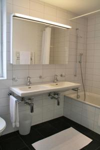 ein Badezimmer mit einem Waschbecken, einem Spiegel und einer Badewanne in der Unterkunft Nest - Nordstrasse 9 in Zug