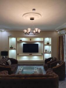 Il comprend un salon avec des canapés et une télévision à écran plat. dans l'établissement Maison d'Hôtes entière Cité Douane Golf Dakar, à Dakar
