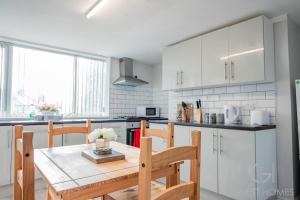 a kitchen with white cabinets and a wooden table and chairs at Guest Homes - Park Cliffe House in Bradford