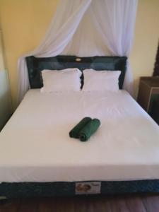 a green bottle laying on a white bed at Why Not Bar And Bungalows in Pawenang