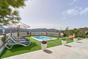 a backyard with a swimming pool and a lawn with chairs and an umbrella at Entre montañas in Árchez
