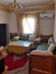 ein Wohnzimmer mit einem Sofa und einem Fenster in der Unterkunft Bel Appartement à El kelaa Des Srarhna in El Kelaa des Srarhna