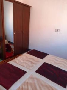 1 dormitorio con cama, puerta y espejo en Bel Appartement à El kelaa Des Srarhna, en El Kelaa des Srarhna