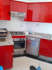 eine rote Küche mit Herd und Spüle in der Unterkunft Bel Appartement à El kelaa Des Srarhna in El Kelaa des Srarhna