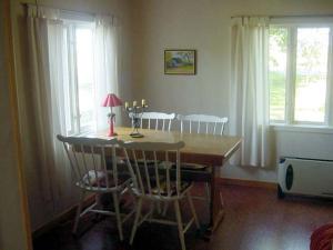 a dining room with a table and chairs and windows at Sydöstra Gotland in Hemse +2 photos