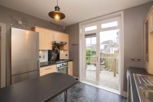 a kitchen with a refrigerator freezer next to a window at Dwellcome Home Ltd 3 Double Bedroom Semi with Garden and Drive in Aberdeen