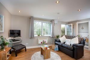 a living room with a leather couch and a tv at Puffin Leigh Cottages in Seaton