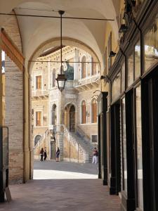 Une allée dans un bâtiment avec des gens qui le descendent dans l'établissement Casa vacanze nel centro storico di Fermo Happy Song, à Fermo