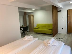 a room with two beds and a green couch at Wonderland apartment in Bistriţa