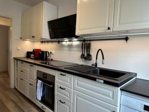 una cocina con armarios blancos y fregadero en MM Lodge - Apartments in Innenstadtlage mit Parkplatz en Augsburg