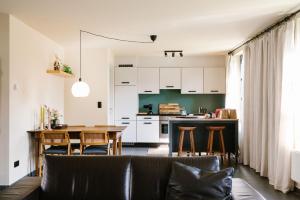 ein Wohnzimmer und eine Küche mit einem Sofa und einem Tisch in der Unterkunft Hoeve de Reetjens - La Gouvernante in Bilzen
