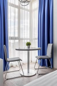 a table and two chairs in a room with blue curtains at barasport city apartments in Kyiv