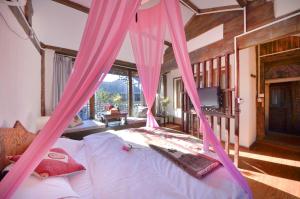 a bedroom with a bed with pink drapes at Lewo Guest House in Lijiang