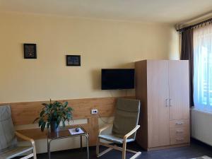 a living room with two chairs and a tv and a cabinet at Adél Apartman in Sárvár