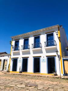 biały budynek z niebieskimi oknami na ulicy w obiekcie Pousada Mãe D'Água w mieście Tiradentes