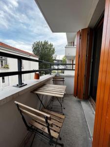 un balcón con 2 bancos y una mesa en un edificio en Appartement Porte de Paris / Stade de France, en Saint-Denis