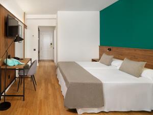 1 dormitorio con 2 camas, escritorio y TV en FERGUS Puerto de la Cruz, en Puerto de la Cruz