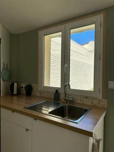 a kitchen with a sink and two windows at Évasion Balnéaire in Grand-Fort-Philippe