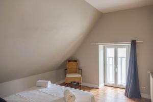 a bedroom with a bed and a chair and a window at Coeur de Blois Maison T3 in Blois