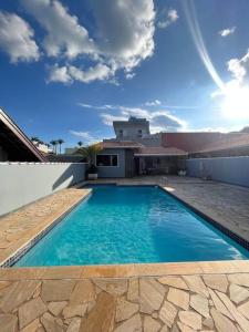 a blue swimming pool in front of a house at Casa com piscina em condomínio fechado in Águas de Lindoia