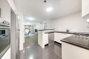 uma cozinha com armários brancos e um forno com placa de fogão em Comfy and Spacious 1B Sydney CBD Apartment in Central em Sydney
