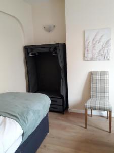 a bedroom with a bed and a chair in it at Luxury 4 Bedroom City Centre Retreat FREE PARKING & FREE WIFI in Bedford