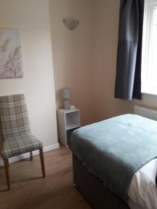 a bedroom with a bed and a chair and a window at Luxury 4 Bedroom City Centre Retreat FREE PARKING & FREE WIFI in Bedford