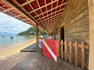 a building with a red fence on the beach at Pousada Frezza Mergulho in Praia Vermelha