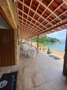 een patio met tafels en stoelen en uitzicht op de oceaan bij Pousada Frezza Mergulho in Praia Vermelha