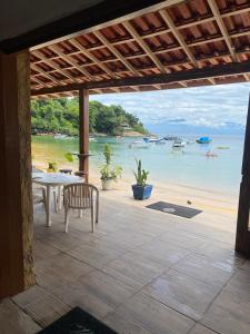 patio con mesa y vistas a la playa en Pousada Frezza Mergulho, en Praia Vermelha