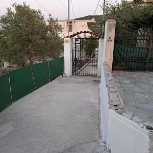a gate to a building with a green fence at Ξενώνας Vasiliki in Vathí