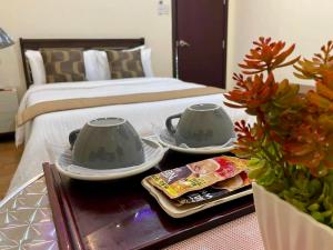 Hillside Hotel في سان خوسيه: غرفة نوم بسرير وطاولة مع كوبين شاي