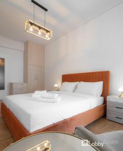 a bedroom with a large white bed and a table at Herod Apartment by LobbySquare in Athens