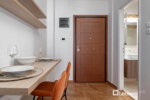 a dining room with a table and a wooden door at Herod Apartment by LobbySquare in Athens
