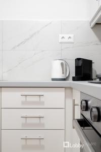 a white kitchen with white cabinets and a appliance at Herod Apartment by LobbySquare in Athens