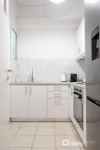 a white kitchen with white cabinets and a sink at Herod Apartment by LobbySquare in Athens +23 photos